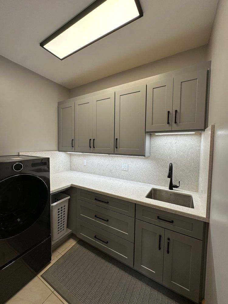 A laundry room with a washer and dryer , sink , and cabinets.