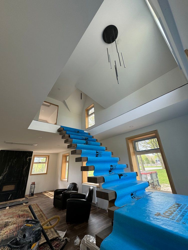 A living room with a staircase covered in blue plastic wrap.