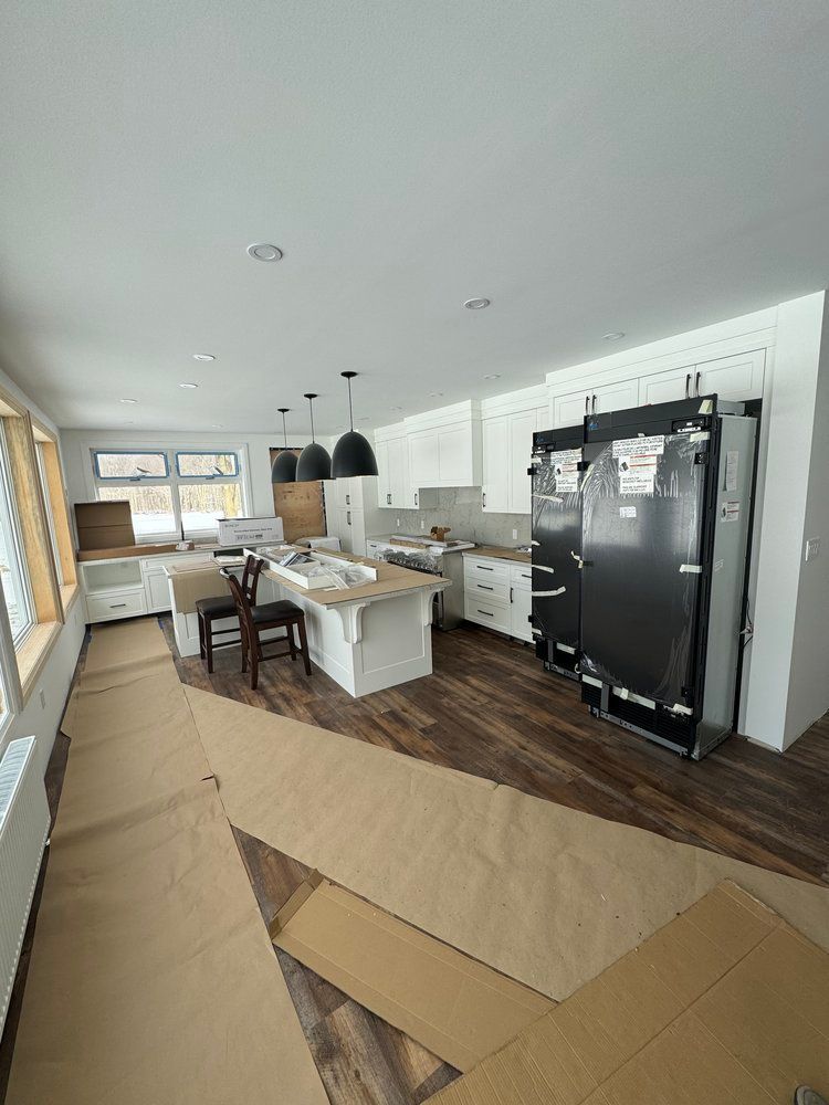 A kitchen with a refrigerator , sink , chairs and a table.