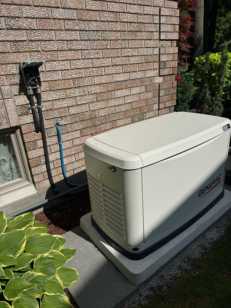 A white generator is sitting in front of a brick building.