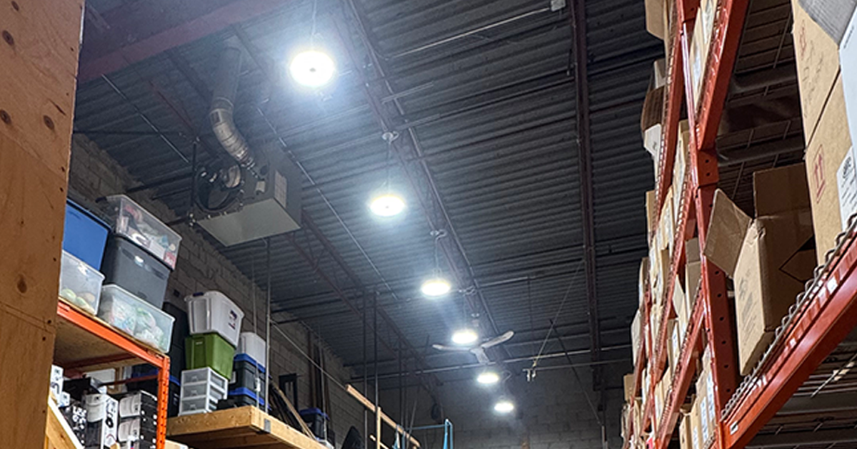 Warehouse interior with rows of shelving and bright overhead lights. Boxes and items fill the shelves.