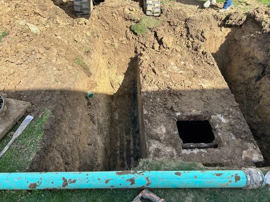 A blue pipe is sitting in the dirt next to a hole in the ground.