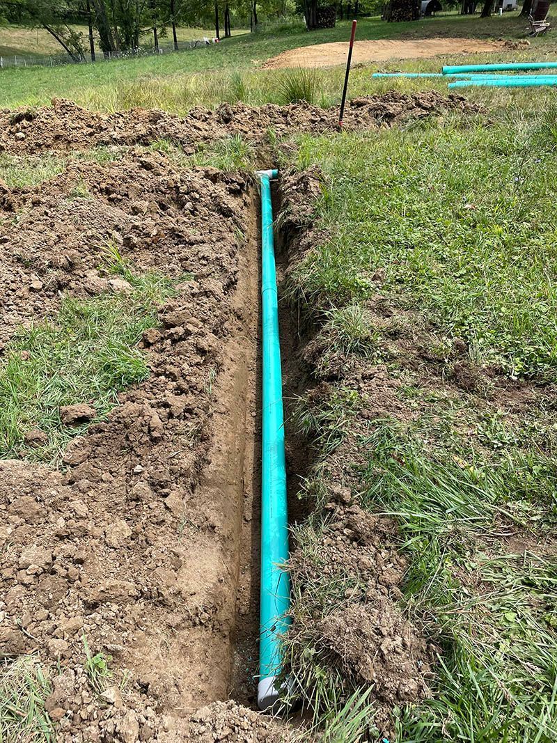 A green pipe is sitting in the middle of a dirt field.