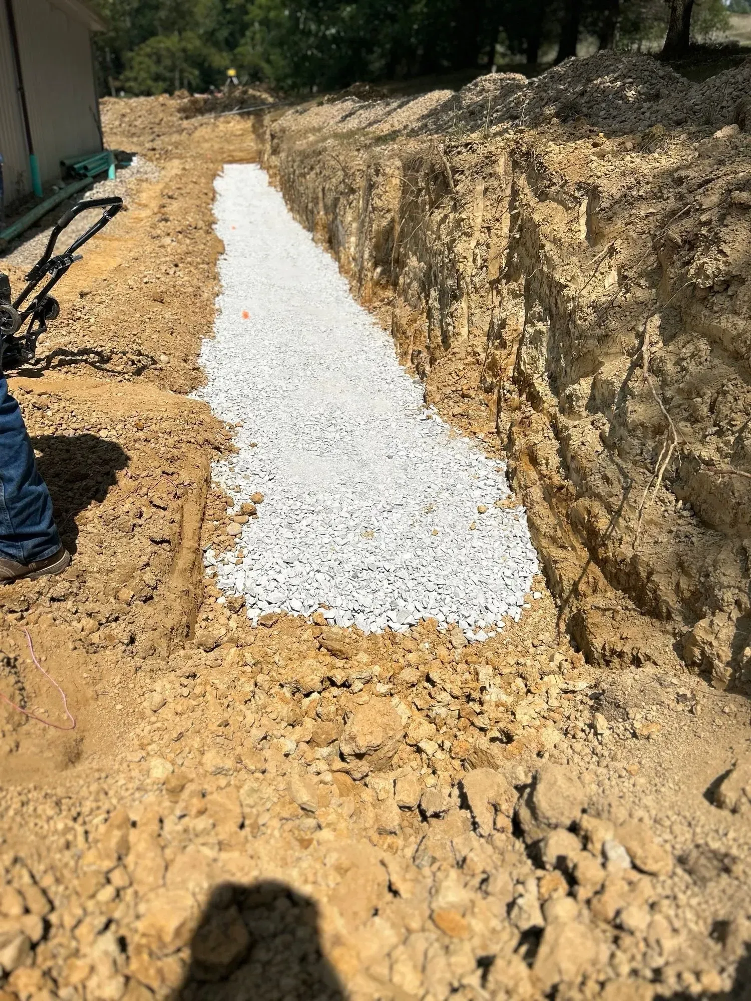 A person is standing in the dirt next to a pile of gravel.