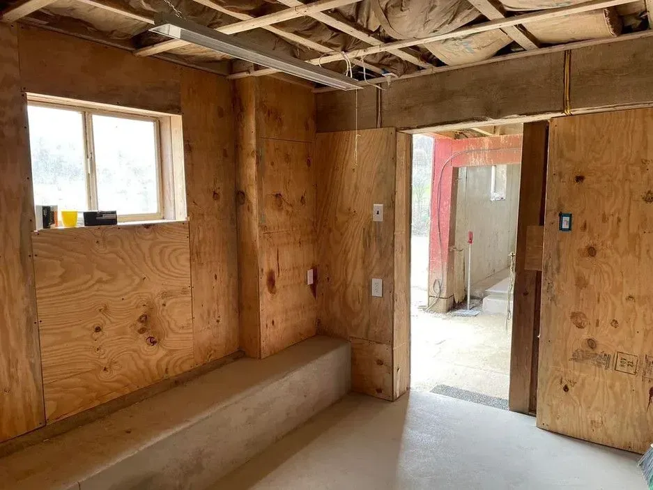 A room with wooden walls and a window in a building under construction.