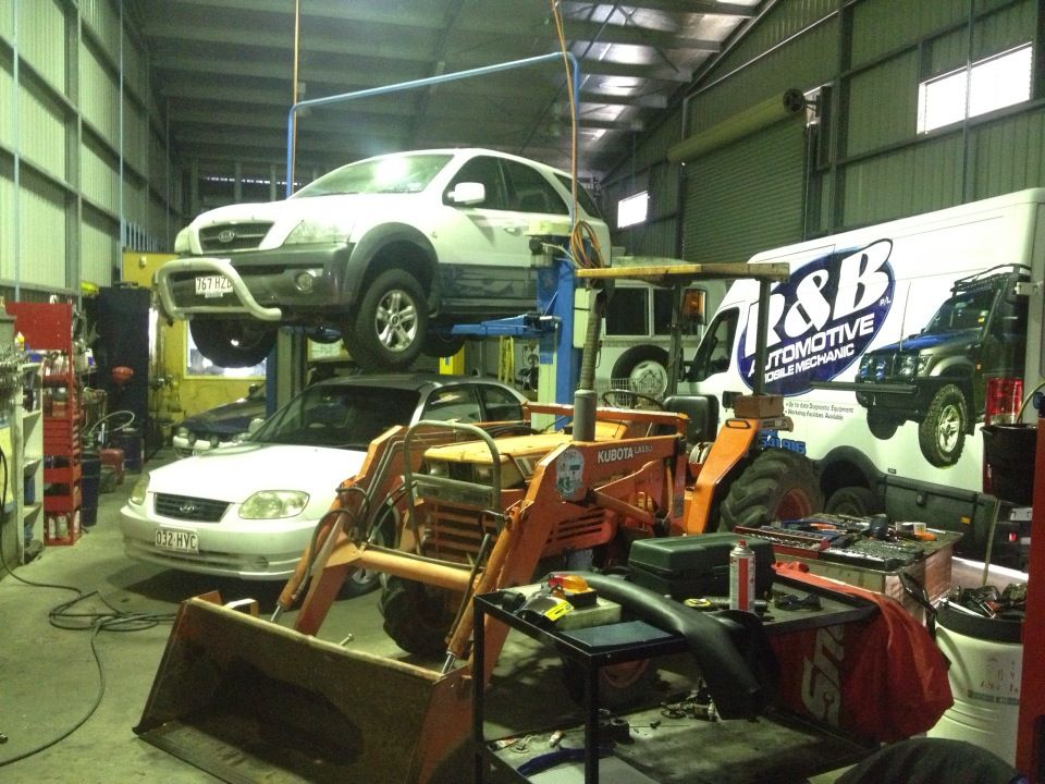 White SUV on Lift, Orange Tractor, White Sedan, and Automotive Van — R&B Automotive PTY LTD In Urangan, QLD