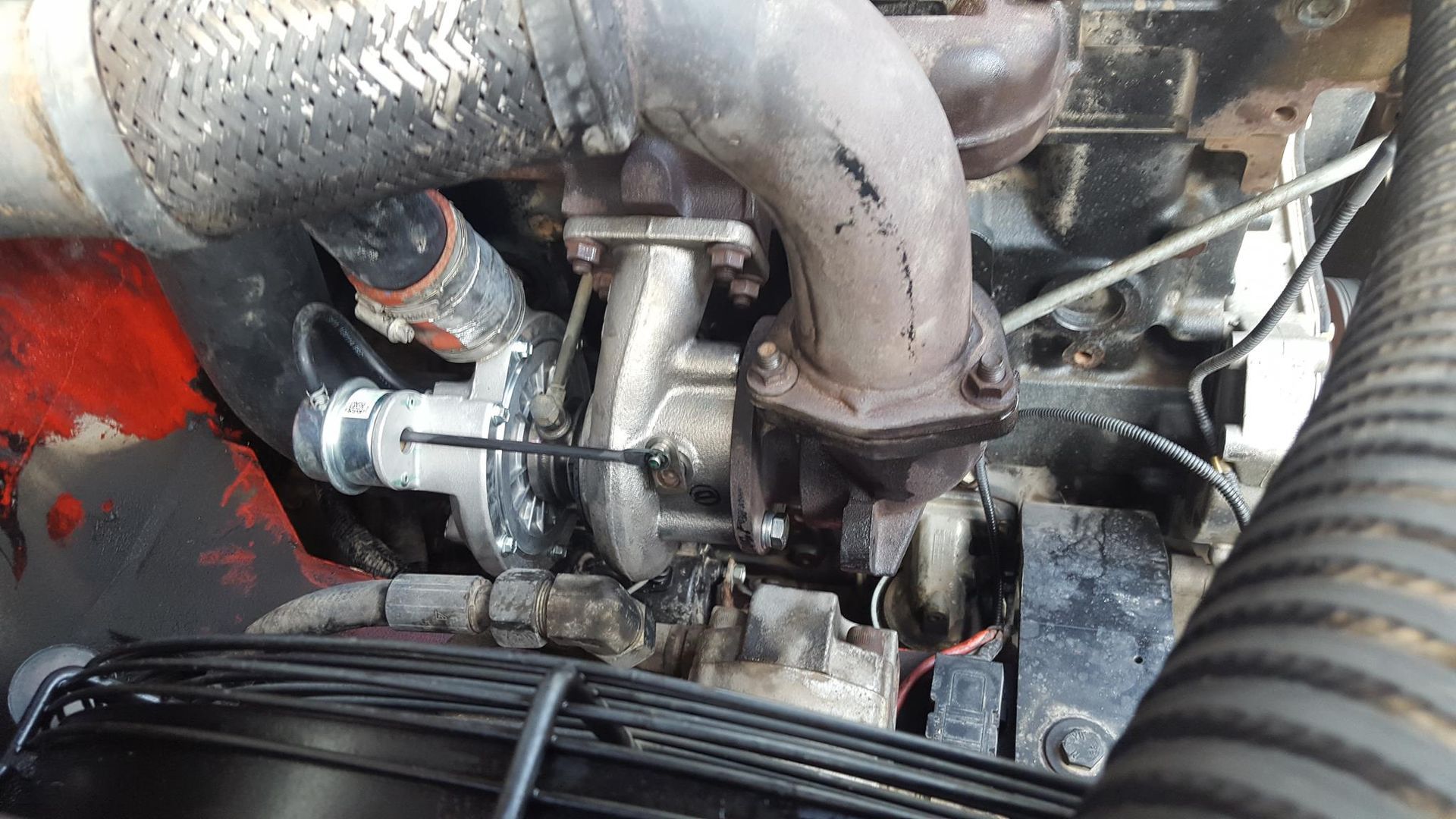 Close-up of a Dirty, Damaged Turbocharger Connected to an Engine With Exhaust Components and a Radiator Fan — R&B Automotive PTY LTD In Maryborough, QLD