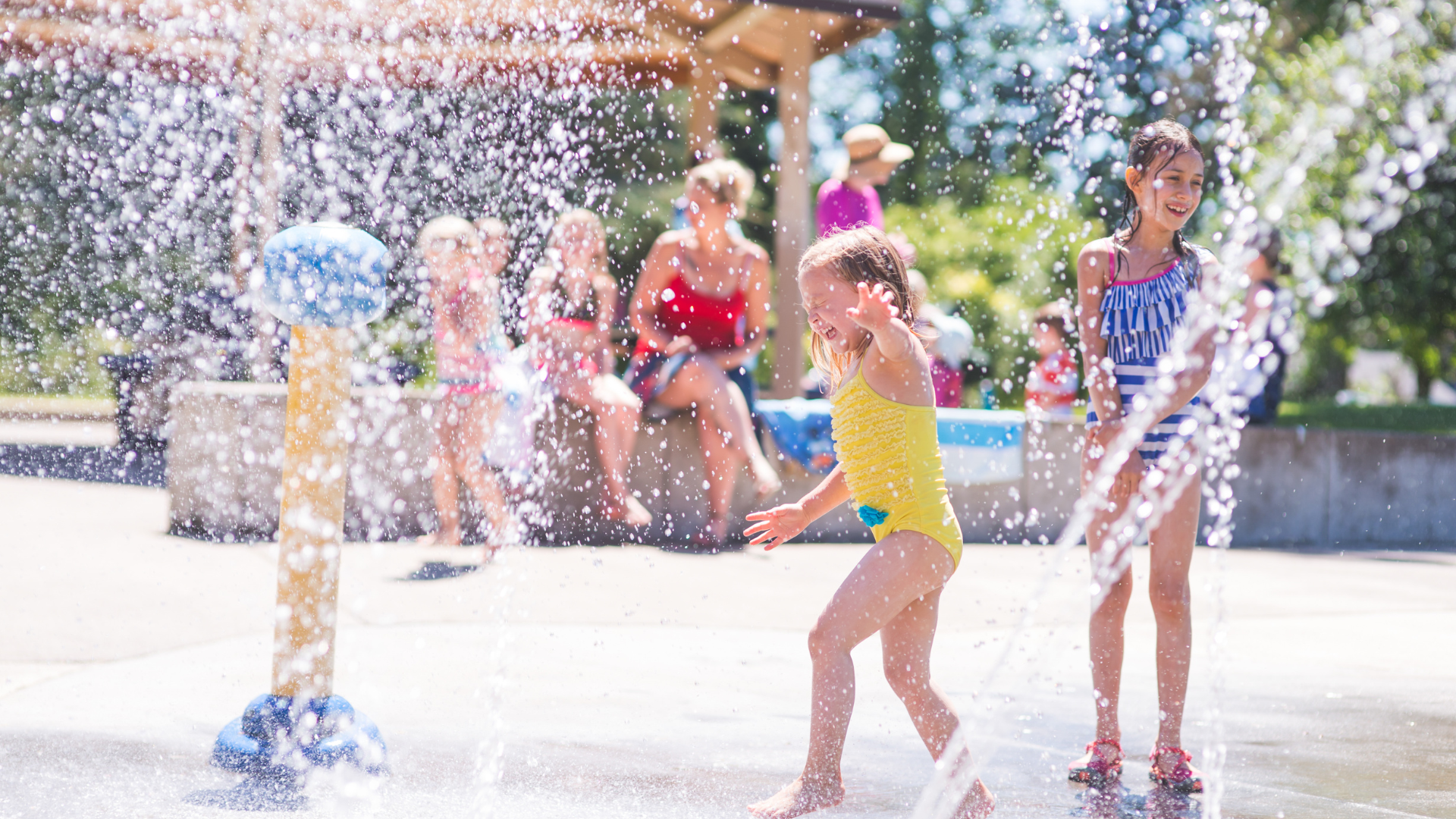 preschool age children in swimsuits playing on a splash pad in August in Kansas City