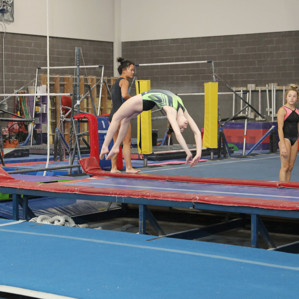 A girl is doing a back handspring on a trampoline