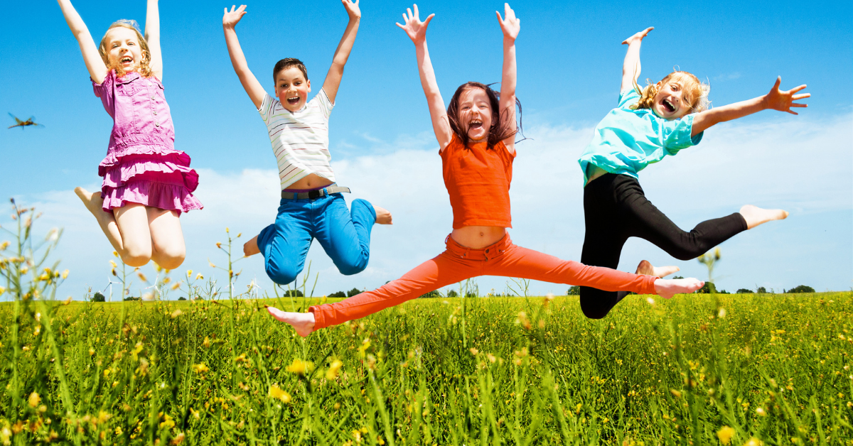 happy kids jumping in a green grass field celebrating after school activities