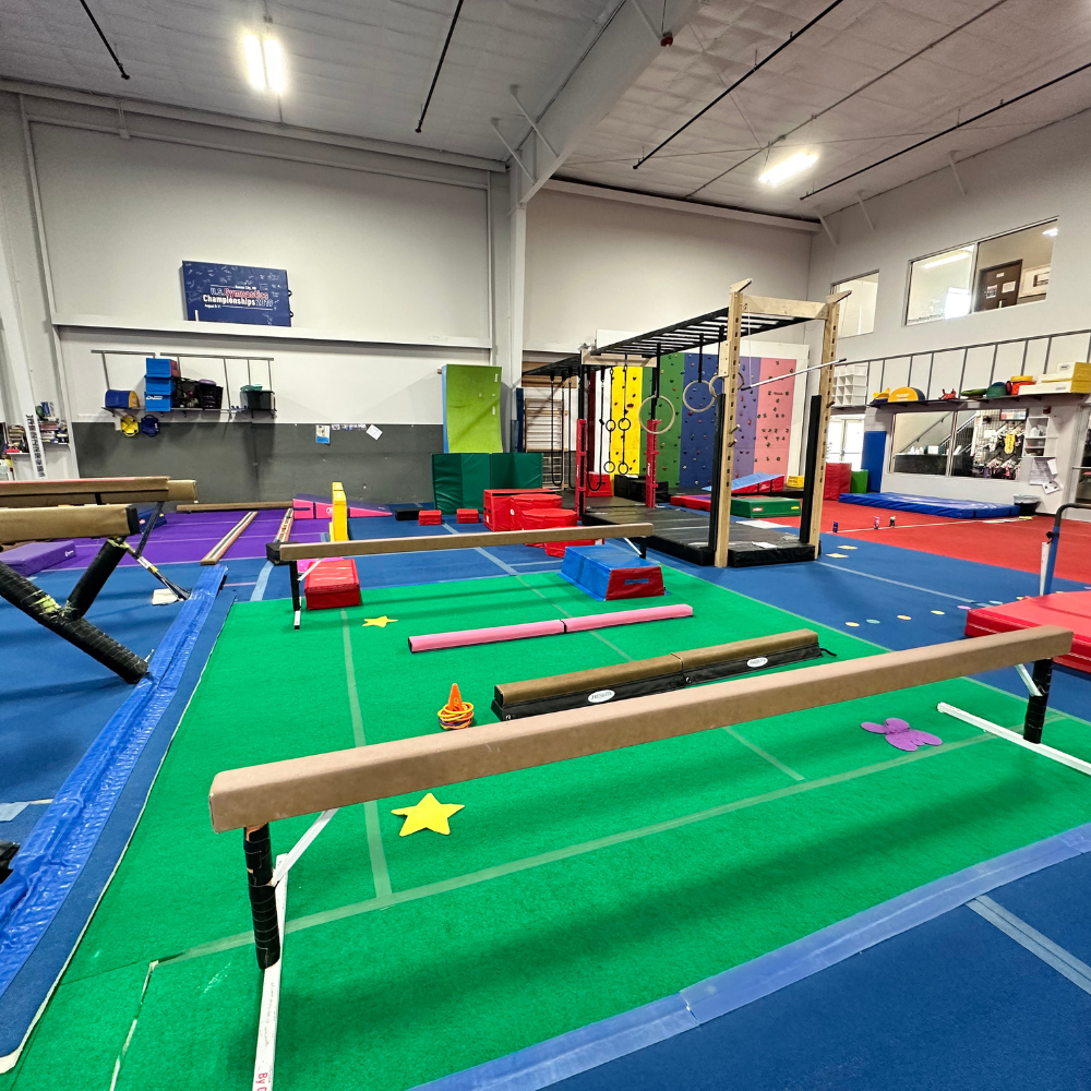 A gymnastics facility with a balance beam and a star on the floor