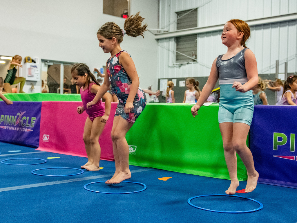 A group of young girls are jumping through hoops in a gym.