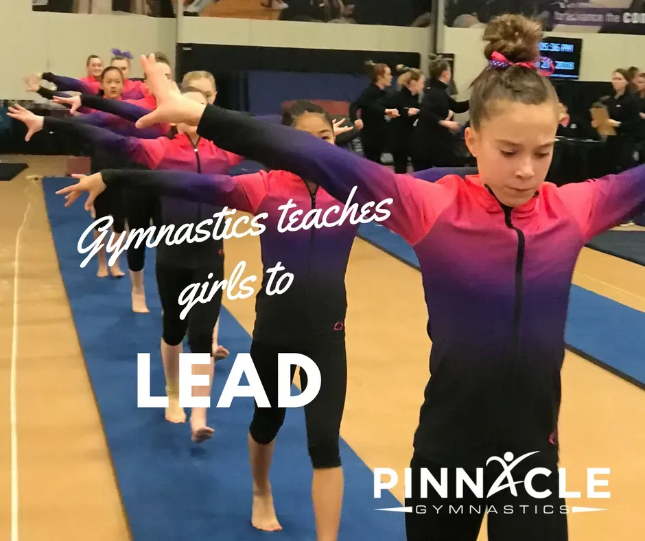Gymnast leading a line of other gymnasts in kicks across the floor.