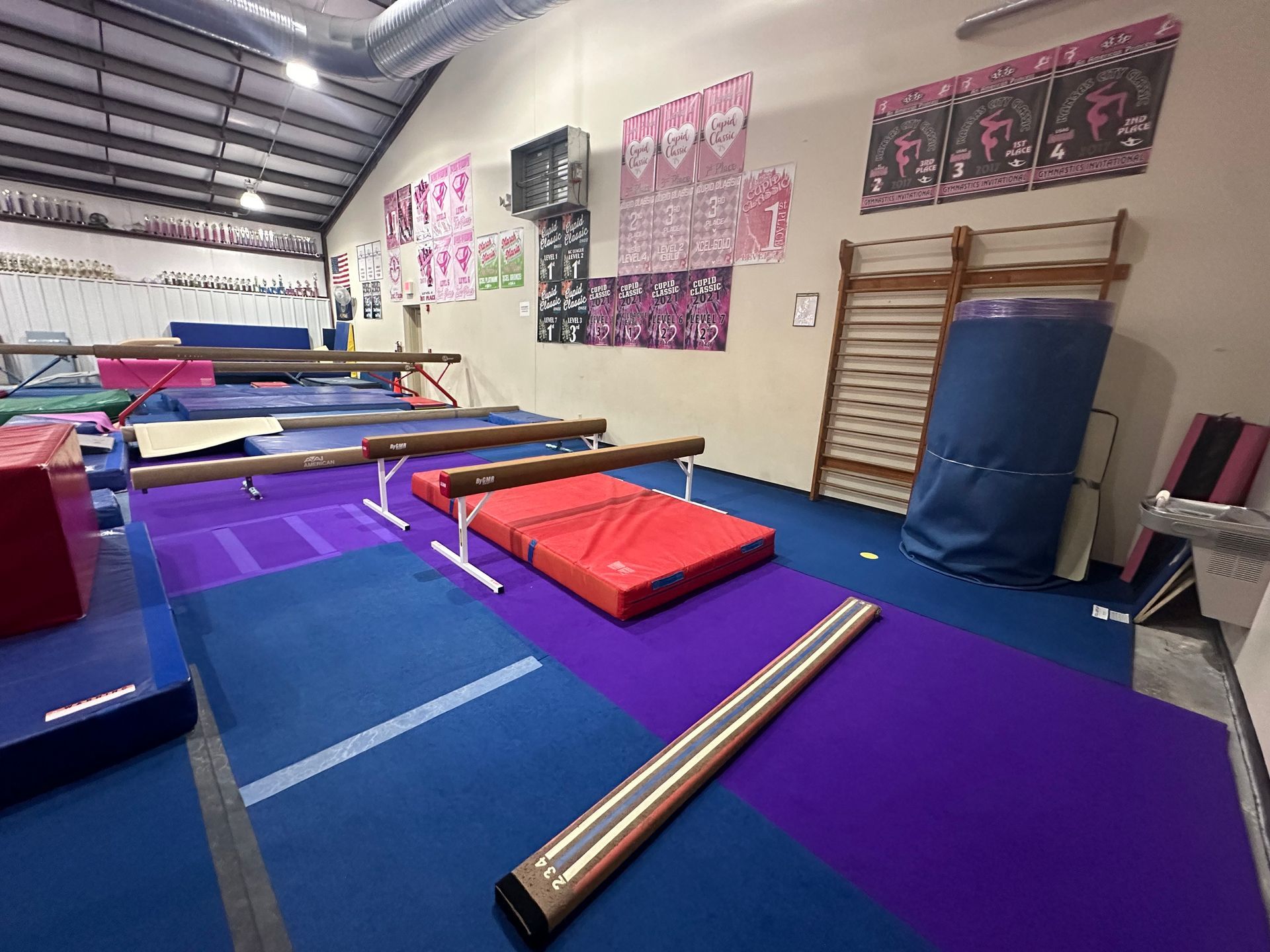 A gymnastics studio filled with a lot of equipment and a purple mat.