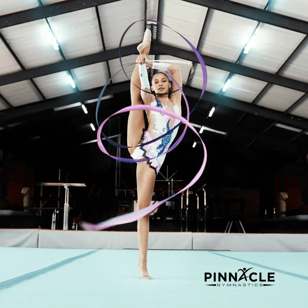 A rhythmic gymnast with a ribbon on a teal carpet