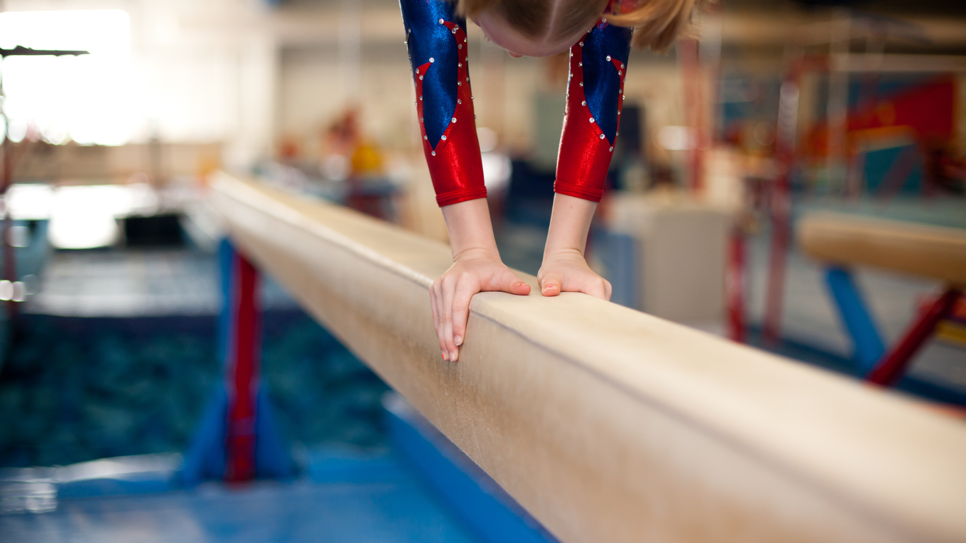 a girl is practicing her handstand on a balance beam