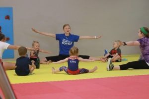 A group of children are doing stretching exercises in a gymnastics club.