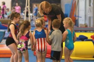 A group of young children are standing in a gym holding hands.