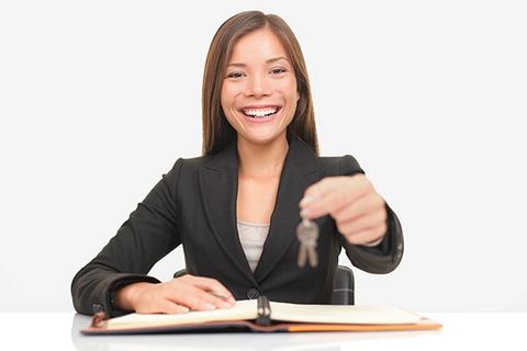 A female property manager holds out a set of keys.