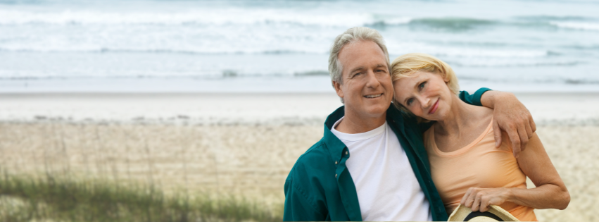 Confident older couple on the beach looking at the camera