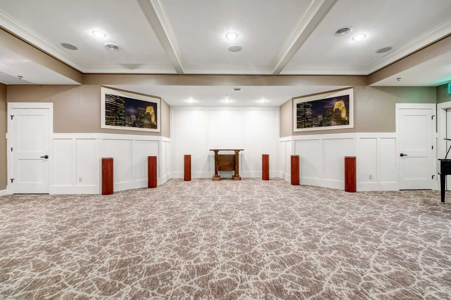 A large room with a carpeted floor and a table in the middle.