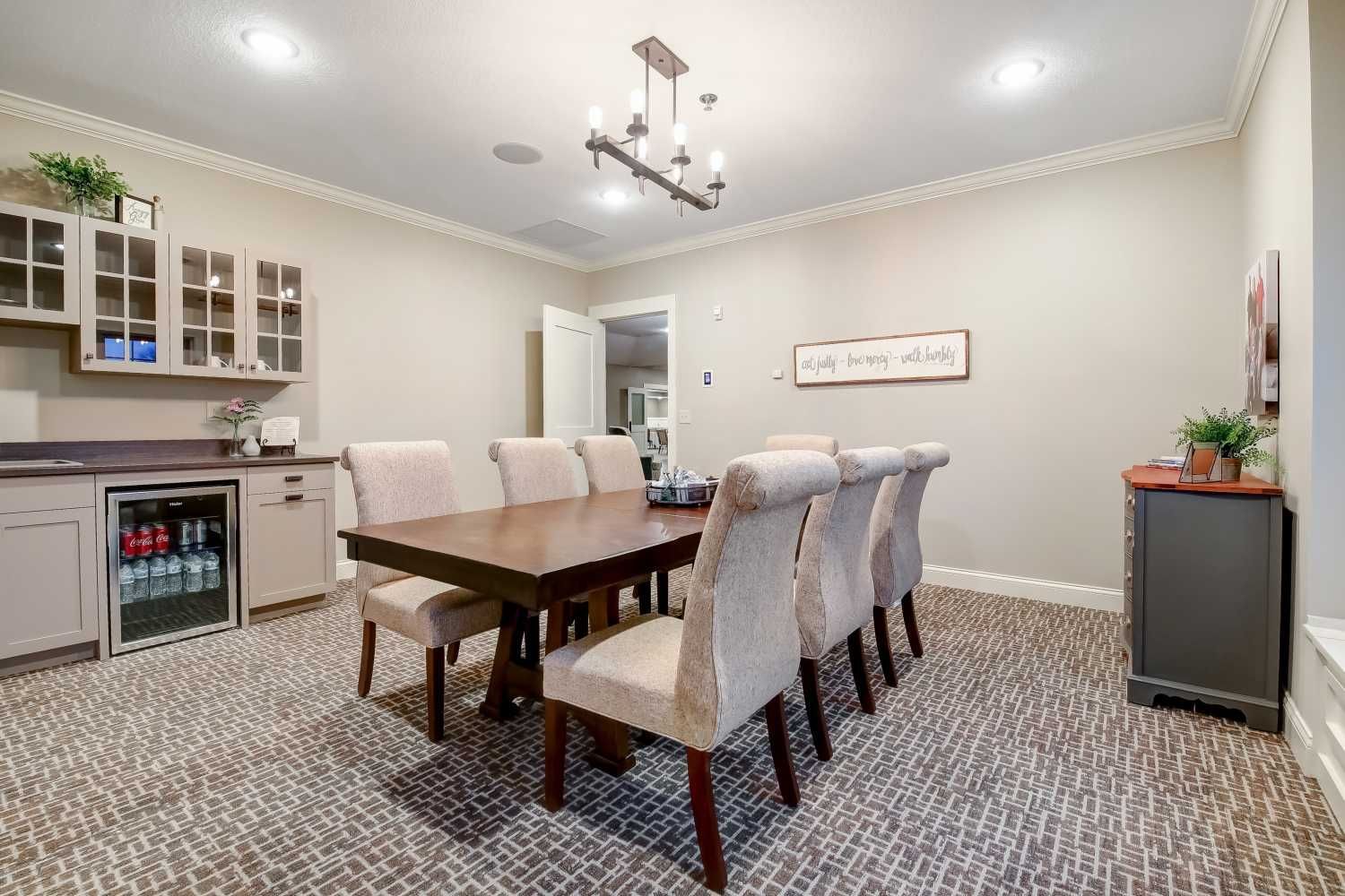 A dining room with a table and chairs and a refrigerator.