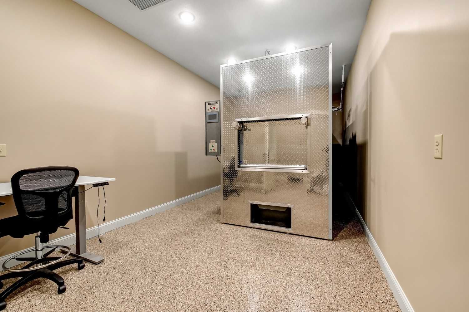 A room with a desk and chair and a large stainless steel oven.