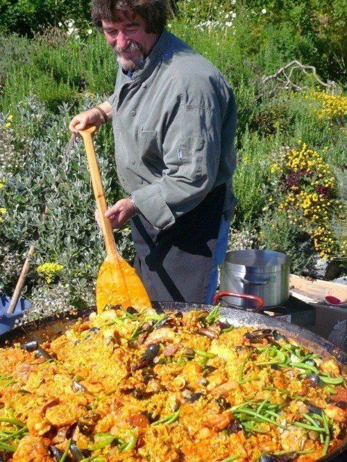 a man is stirring a large pan of food with a wooden spoon