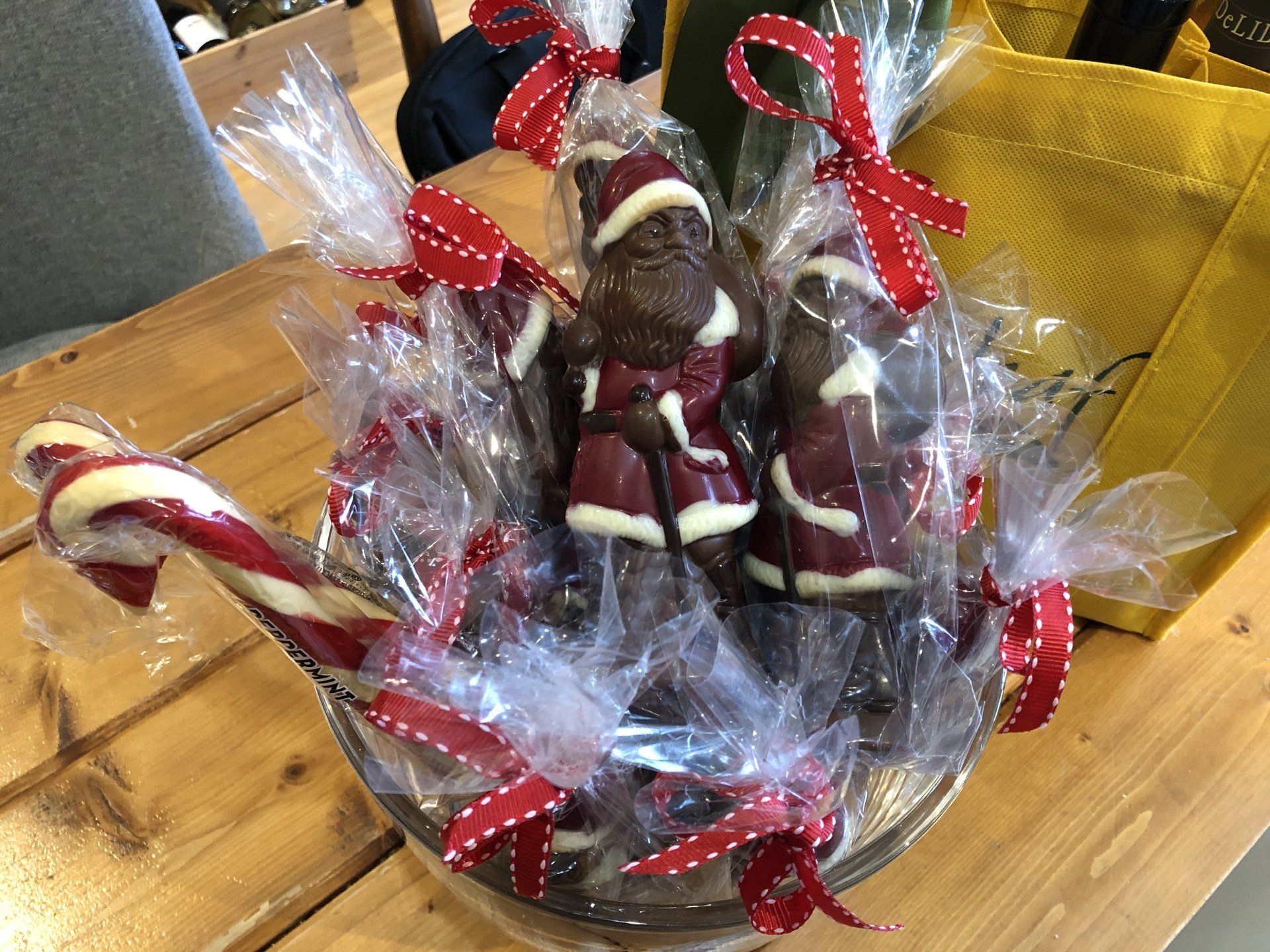 a bowl of chocolate santas and candy canes on a wooden table .