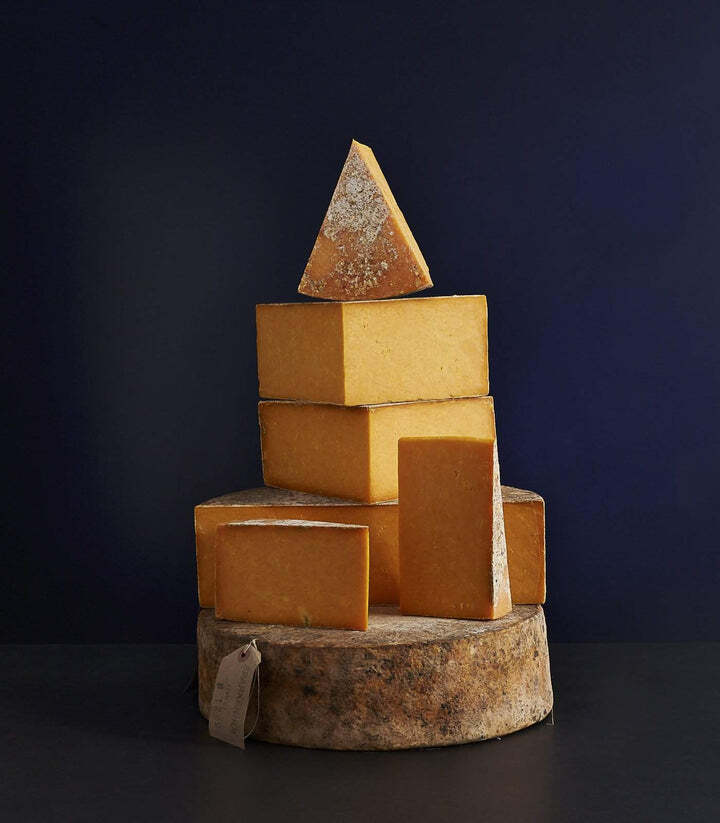 several pieces of cheese are stacked on top of each other on a wooden stump .