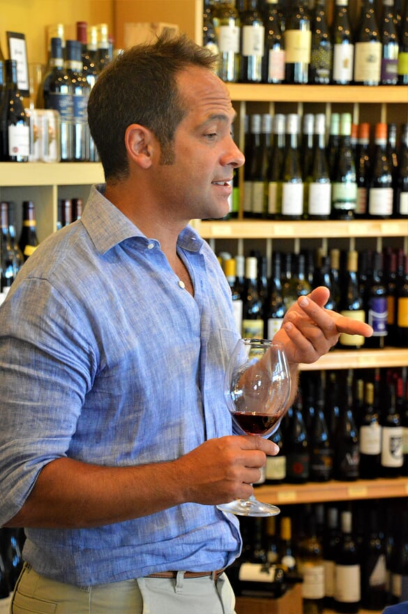 a man in a blue shirt is holding a glass of wine