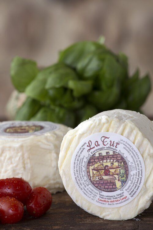two rolls of la cur cheese are sitting on a wooden table next to tomatoes .