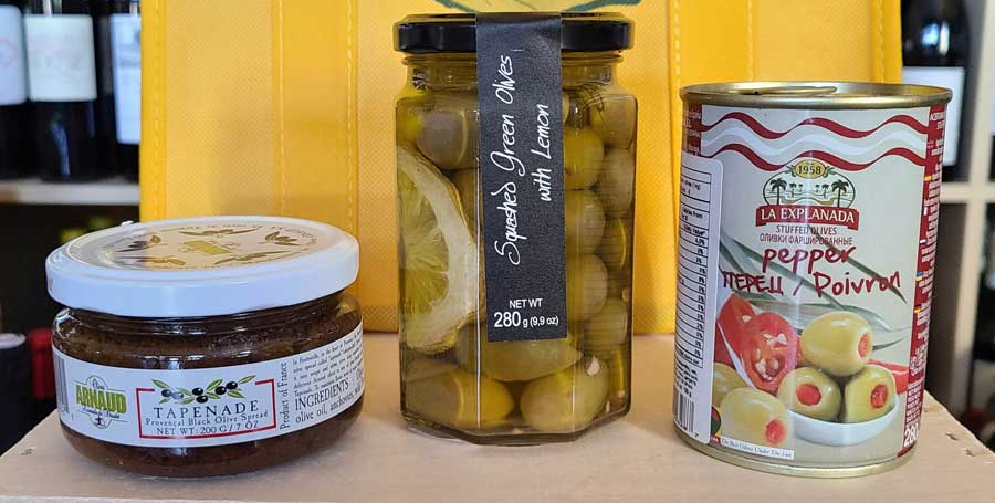 three jars of food are sitting on a wooden table .