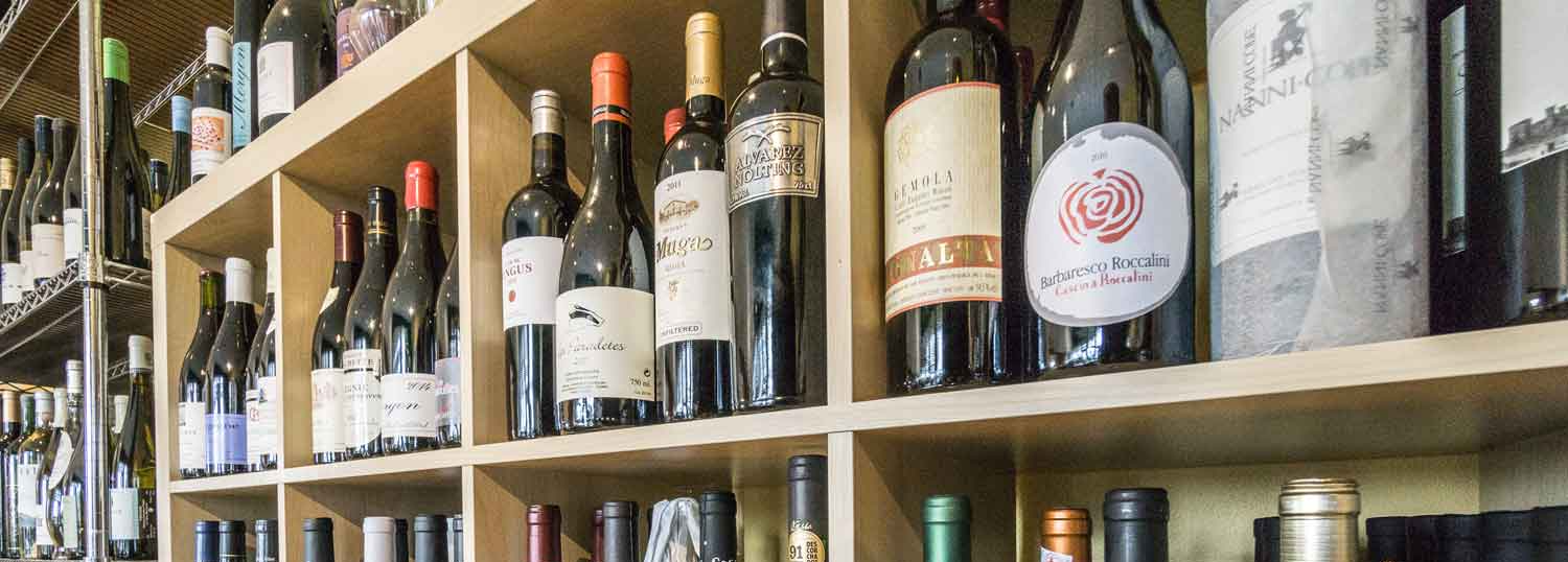 a shelf filled with lots of bottles of wine .