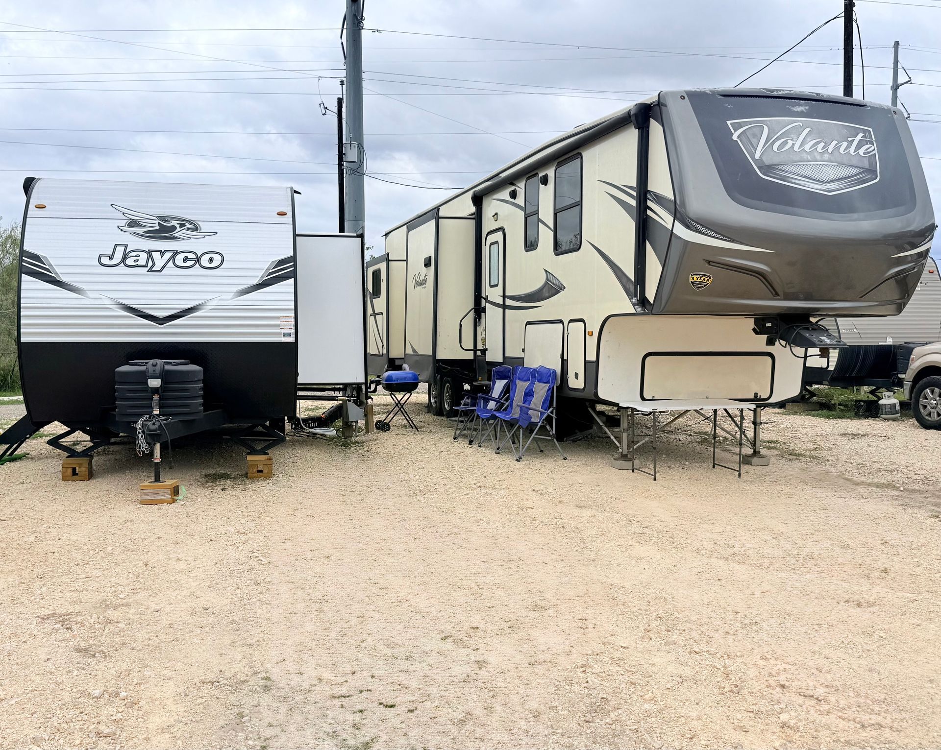 A man and a child are roasting marshmallows over a campfire in front of a rv.
