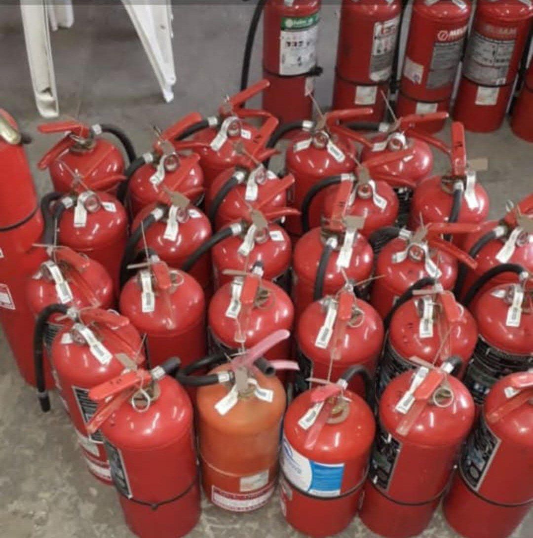 Un montón de extintores rojos están apilados uno encima del otro.