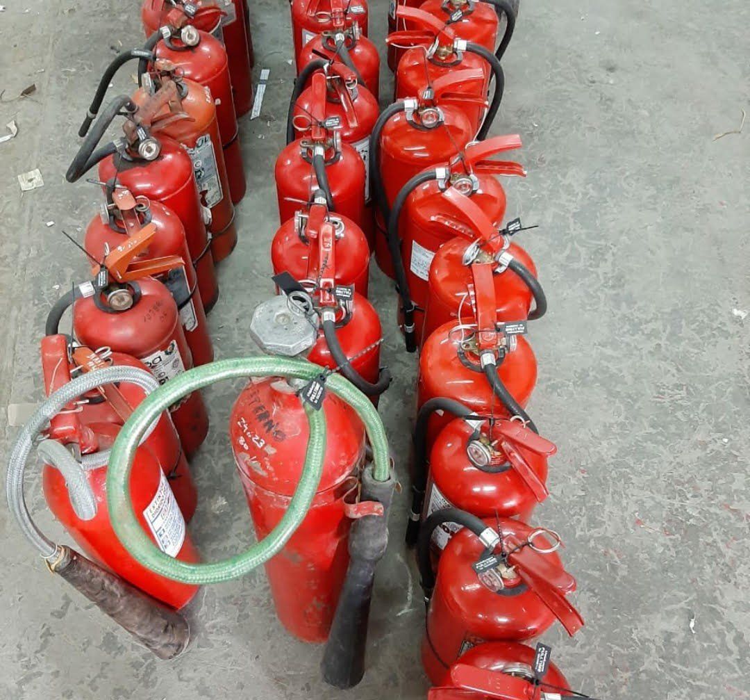 Una fila de extintores rojos están alineados en el suelo.