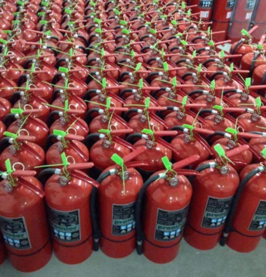 Filas de extintores rojos con mangos verdes