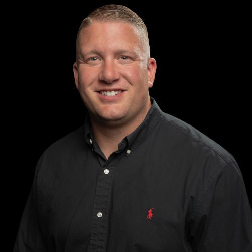 Man in black shirt smiling, against a black background.