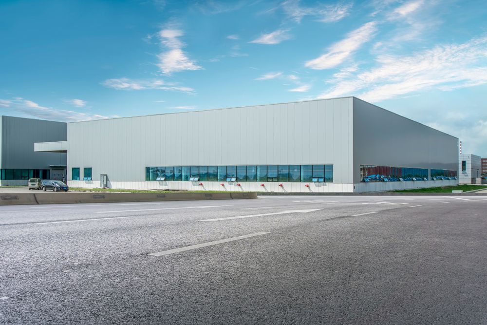 Warehouse building with asphalt in front and blue sky above.