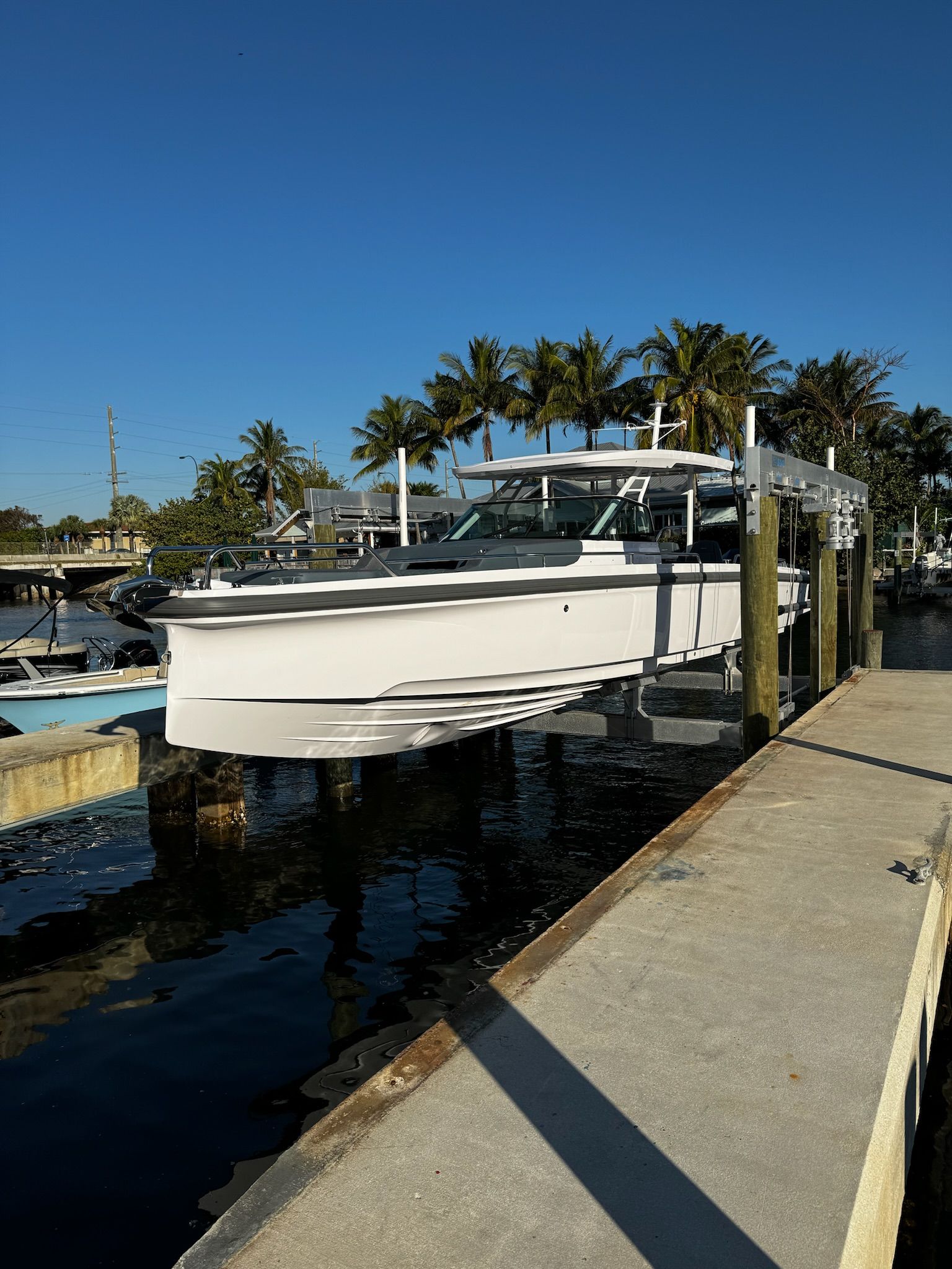 A white boat is docked at a dock with palm trees in the background.