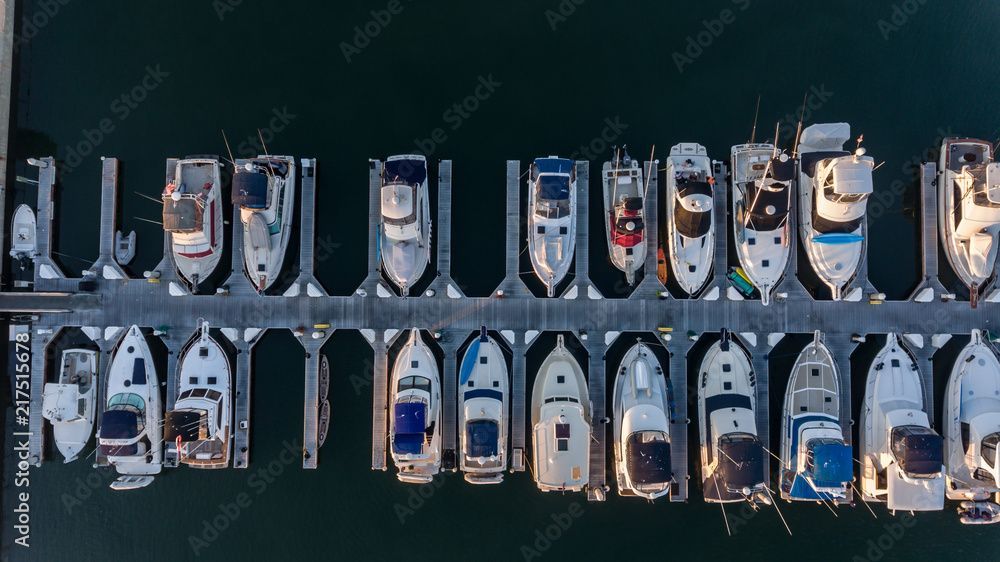 A row of boats are docked in a marina.