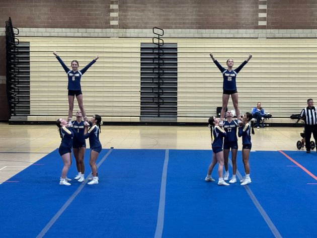 Red, white, and blue pom-poms held high by cheerleaders during a performance.