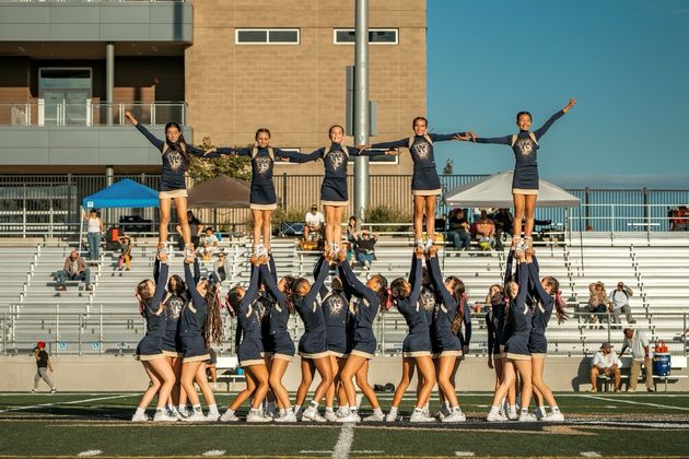 Football player in silver uniform runs with ball on a green field.