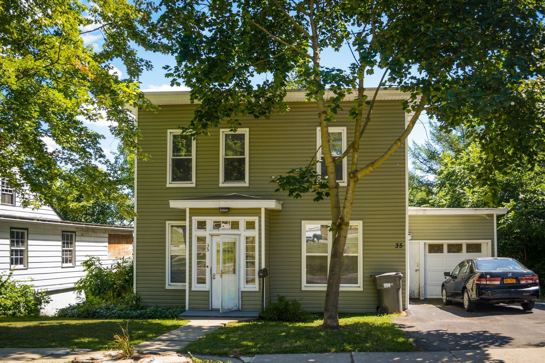35 James Street – Two-story olive-green house with front porch entry and attached garage, partially shaded by trees.
