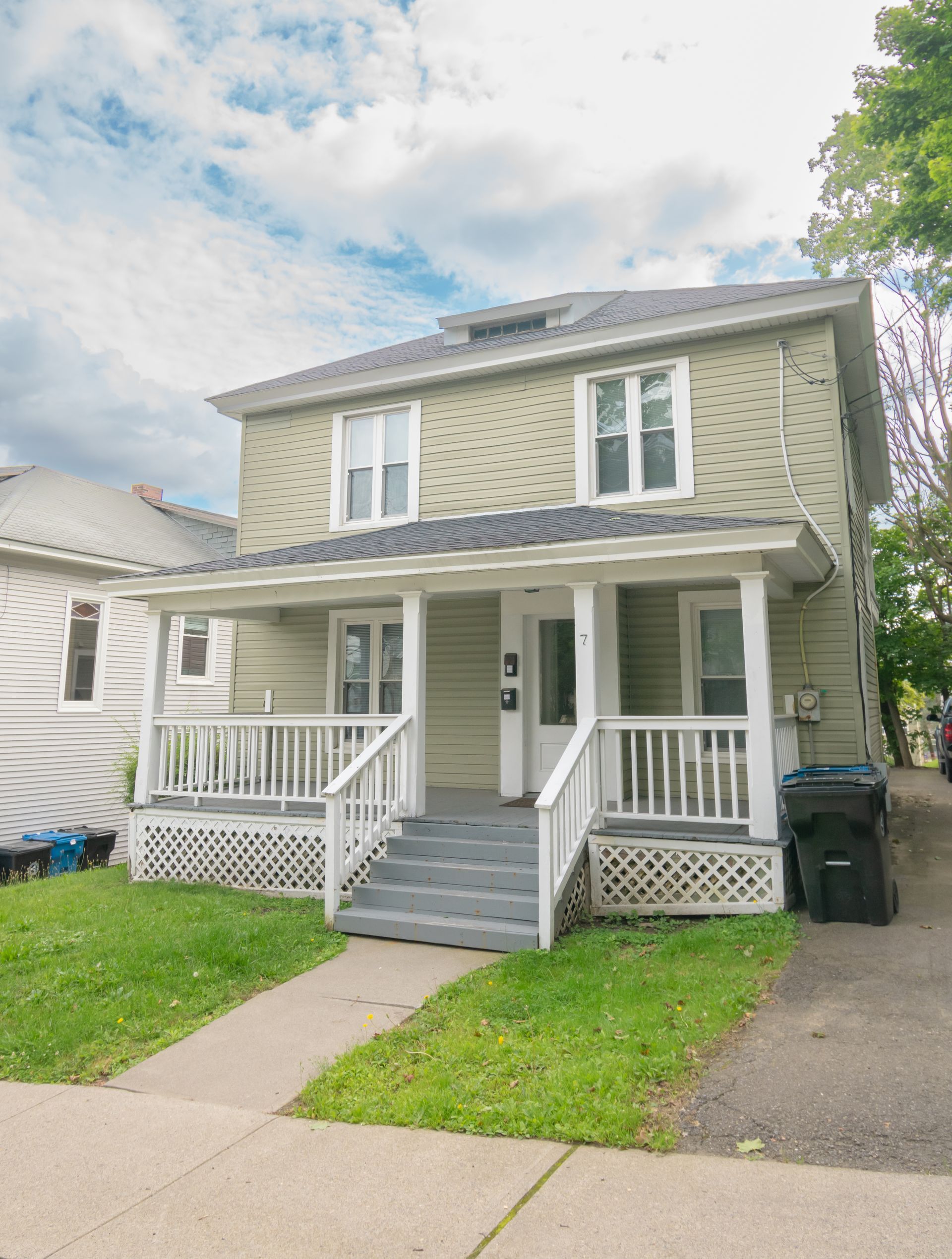 7 Pleasant  – Beige two-story house with a covered front porch and lattice skirting.