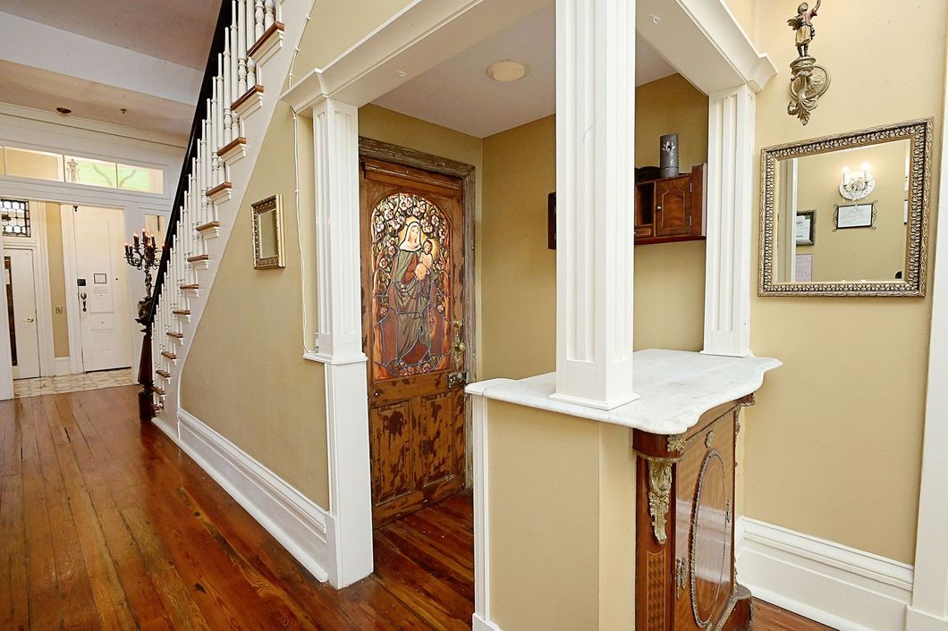 Entryway with hardwood floors, staircase, ornate door, and marble-topped console table; tan walls.