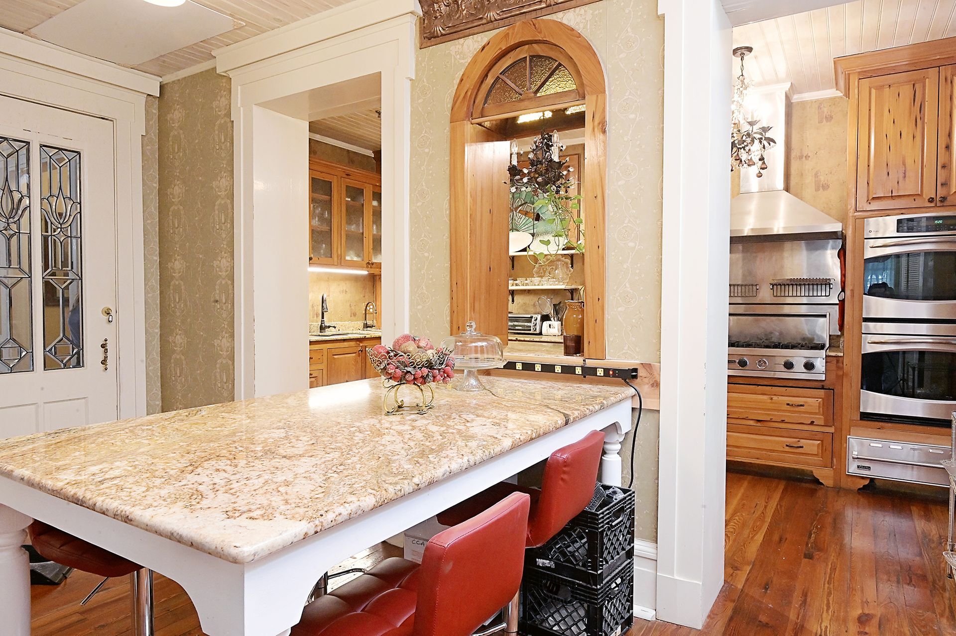 Kitchen with island seating. Features wood cabinets, stainless steel appliances, and a pass-through to a second kitchen area.