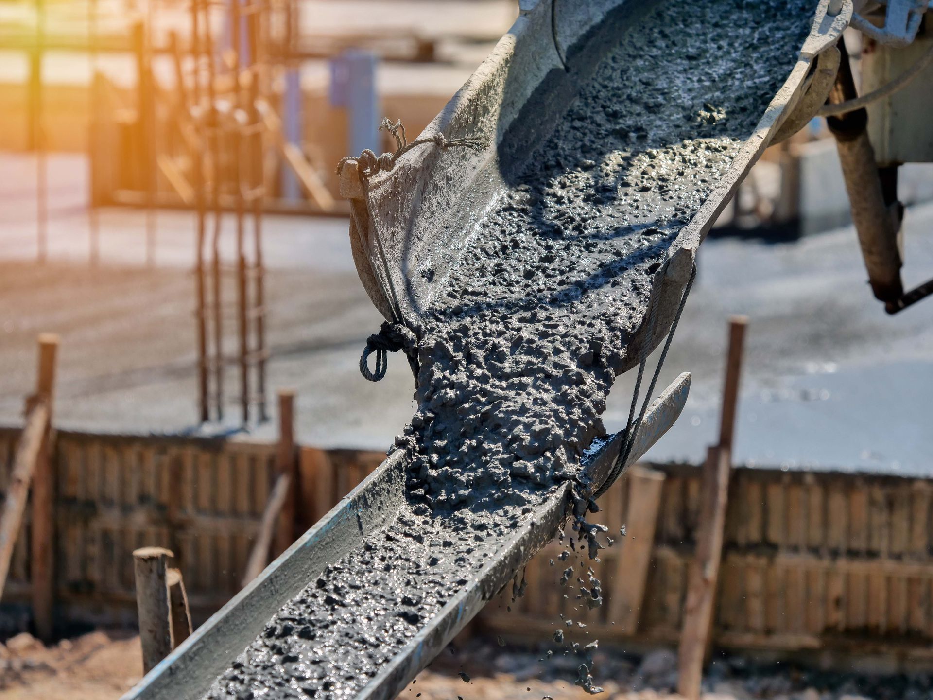 A concrete mixer is pouring concrete into a conveyor belt at a construction site.