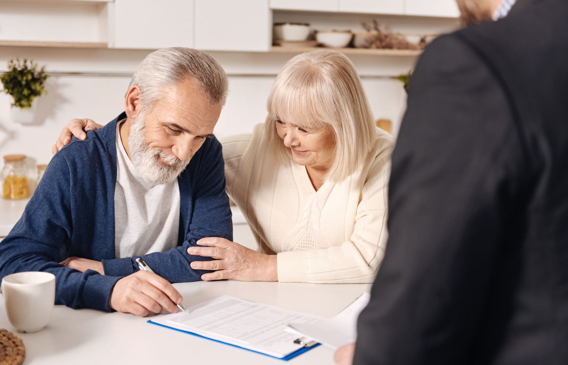 An elderly couple meets with a Social Security lawyer from Milam Law to sign documents at their home